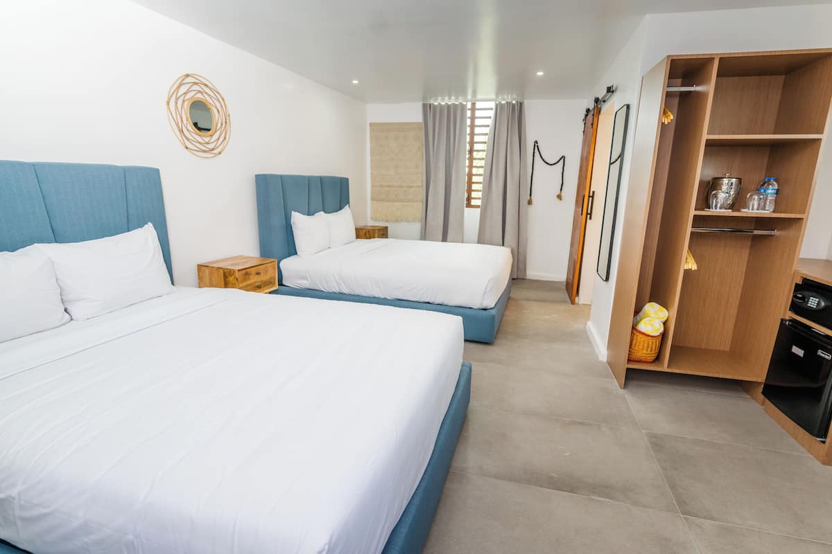 Ein Hotelzimmer mit zwei Betten, einem Schrank, einem kleinen Tisch und einem Spiegel an der Wand.