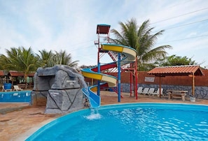 Un parc aquatique comprenant une piscine, une formation rocheuse et un toboggan aquatique.