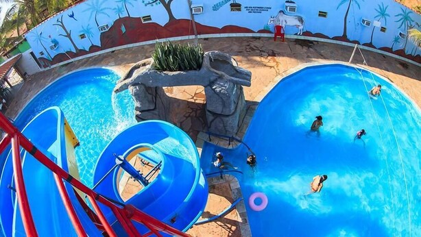 Ein Wasserpark mit zahlreichen Rutschen und Becken, umgeben von einer Wandmalerei mit tropischen Motiven und Tierdarstellungen.