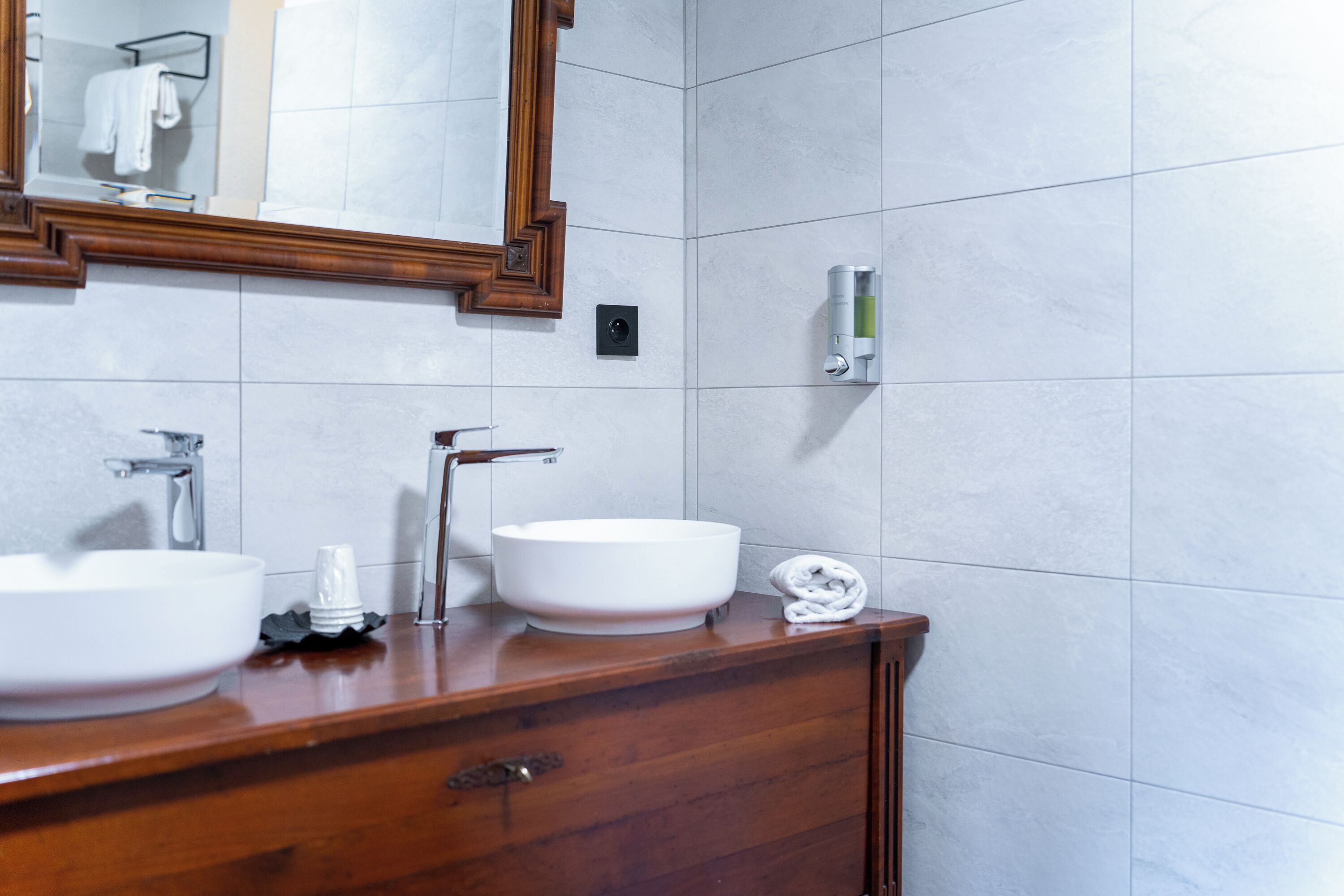 Un baño con dos lavamanos, un espejo y un perchero para toallas.