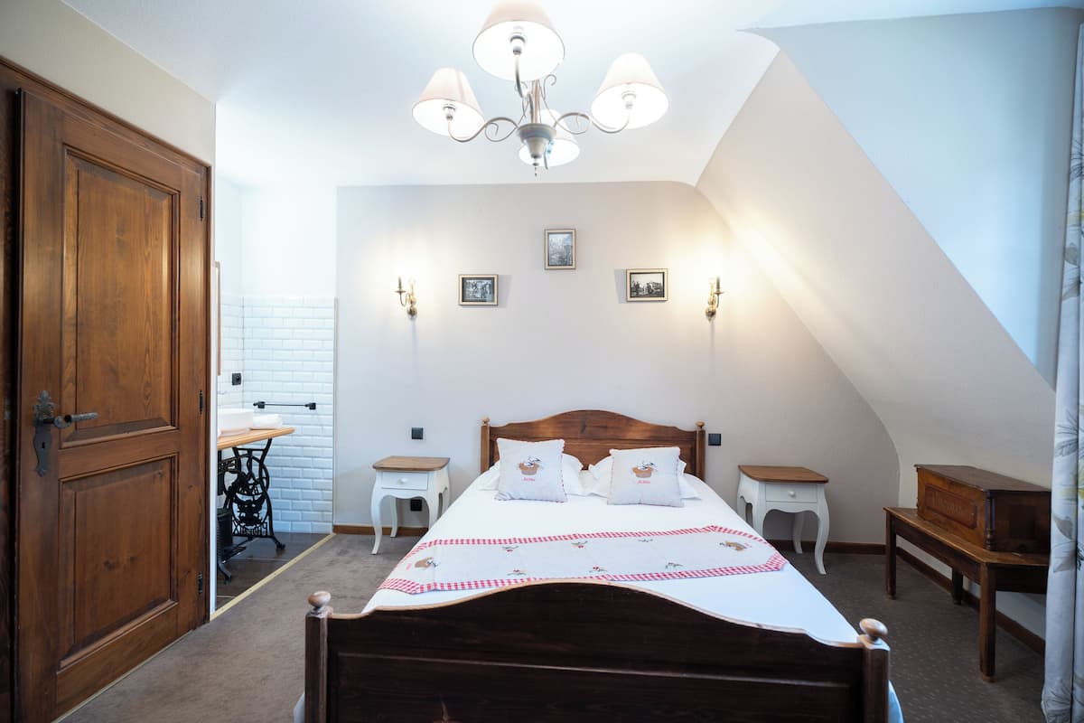 A bedroom with a wooden bed, a chandelier, and a white wall with pictures.