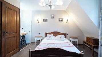 A bedroom with a wooden bed, a chandelier, and a white wall with pictures.
