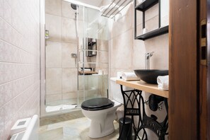A modern bathroom with a glass shower enclosure, a white toilet, and a wooden vanity with a black sink. - Hôtel Berceau du Vigneron (Turckheim)