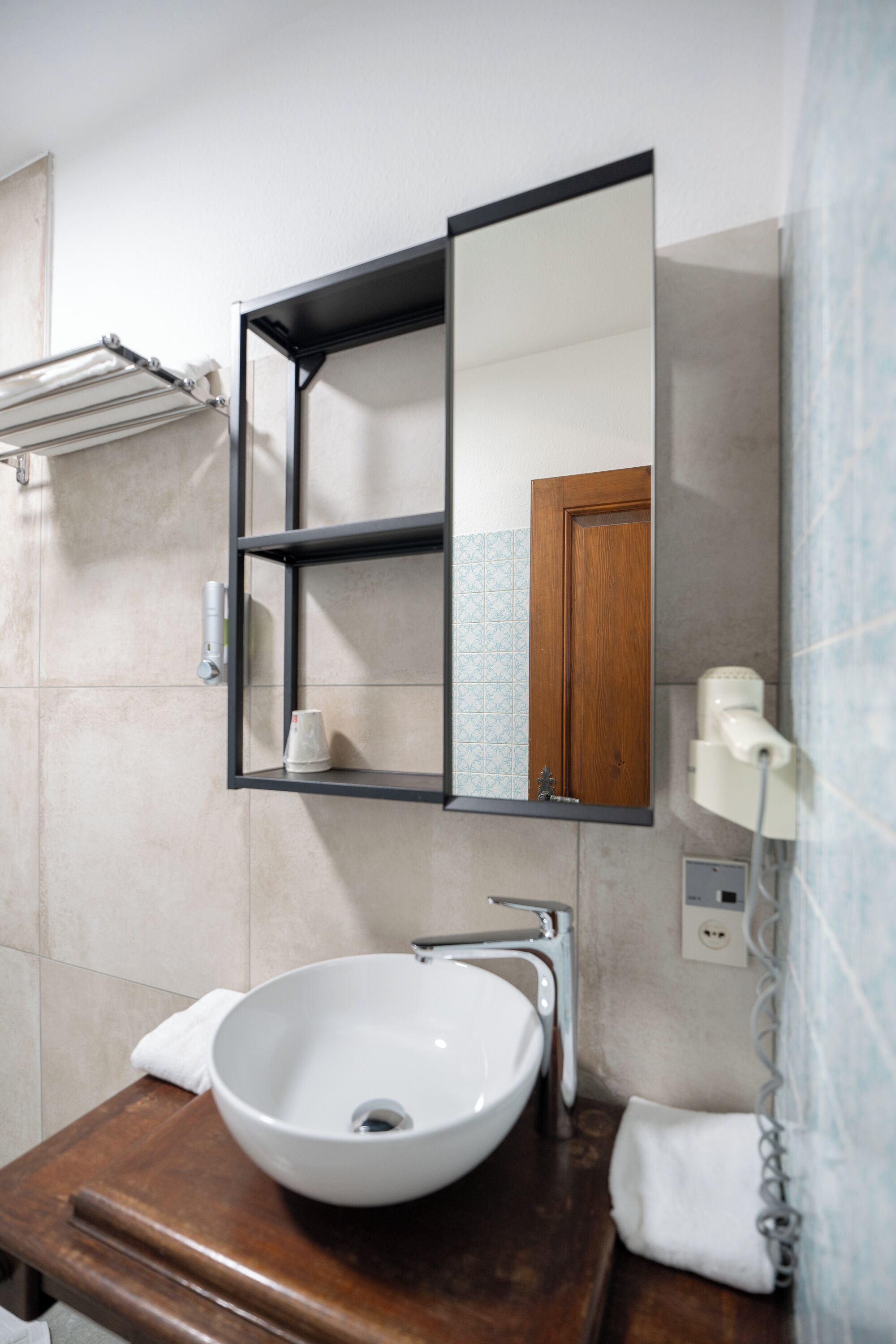 Een badkamer met een wit wastafel, een spiegel, een handdoekhouder en een douchegordijn.