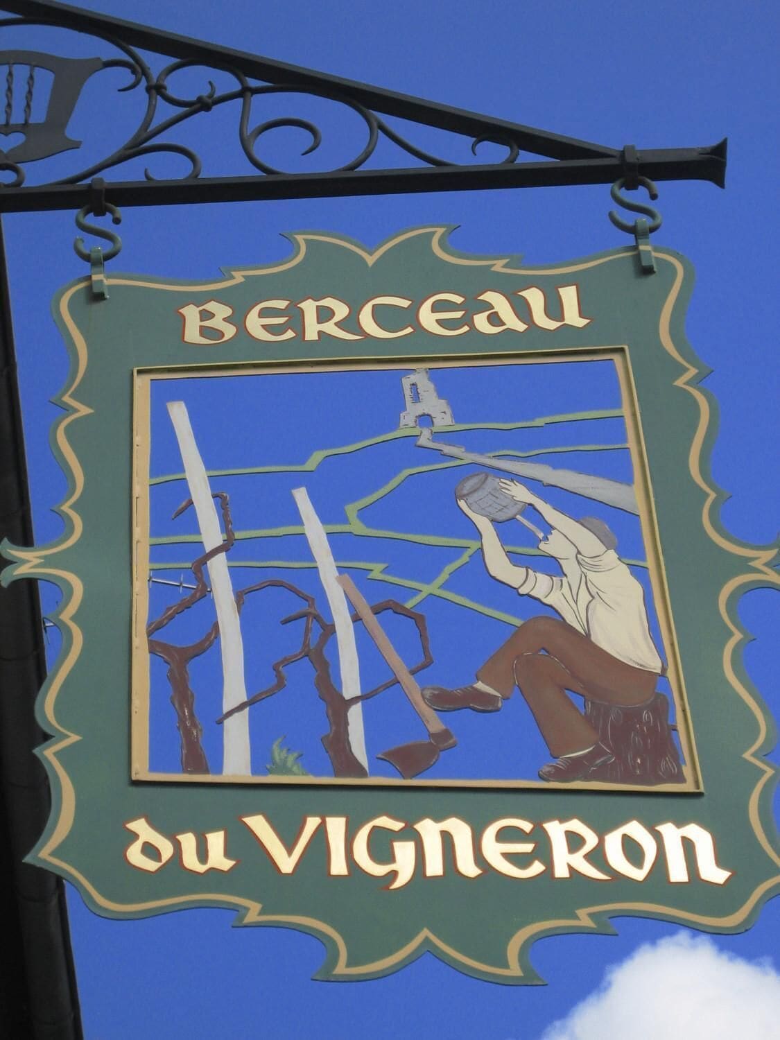 Un letrero con el nombre 'BERCEAUX du VIGNERON' y una ilustración de una persona cortando leña.