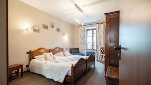 A bedroom with a wooden bed, a nightstand, a wardrobe, and a window with curtains.