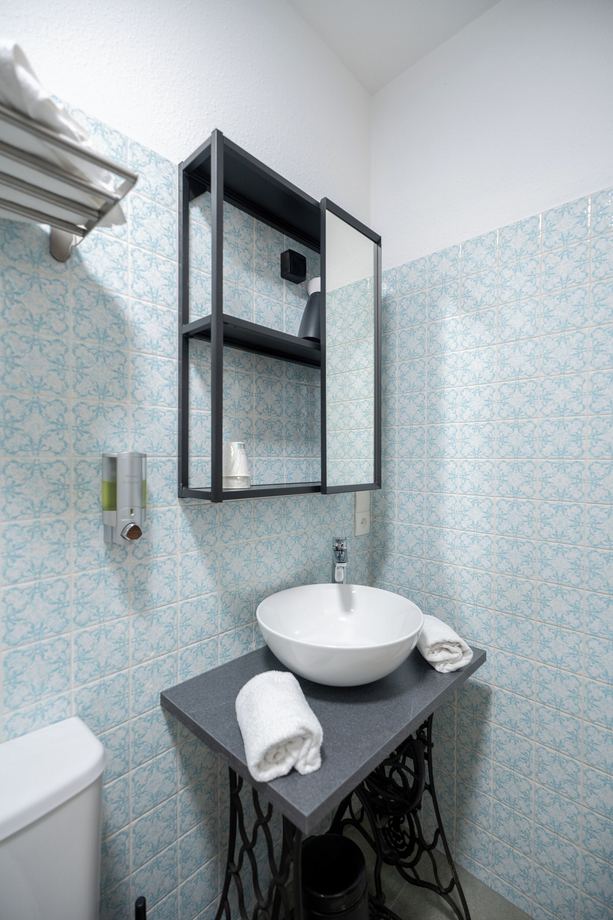 A bathroom with a white sink, a towel, a mirror, and a toilet.