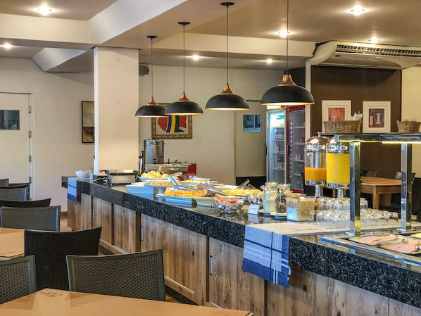 A buffet area with a variety of food items, a refrigerator, and a juice dispenser.