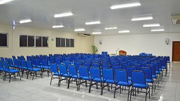 A conference room with rows of blue chairs, a podium, and a large window.