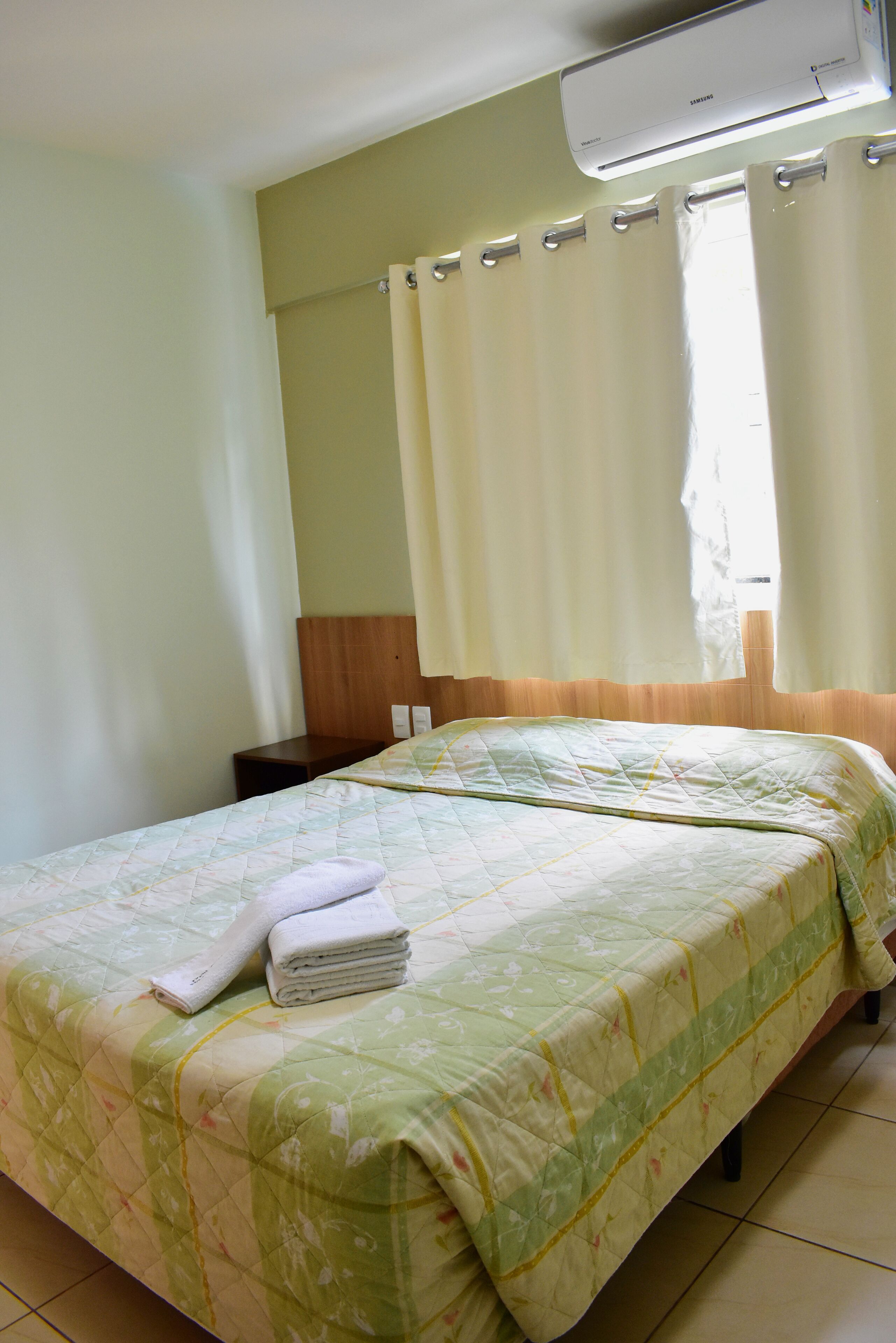 Une chambre d’hôtel équipée d’un lit, d’une table de chevet et d’un climatiseur.