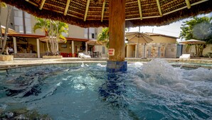 A pool area with a thatched roof, lounge chairs, and a sign indicating a 'Dado Grau' area. - Rio das Pedras Thermas Hotel (Caldas Novas)