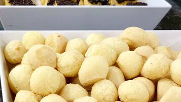 Two white rectangular trays filled with round, yellow pastries and chocolate-topped desserts.