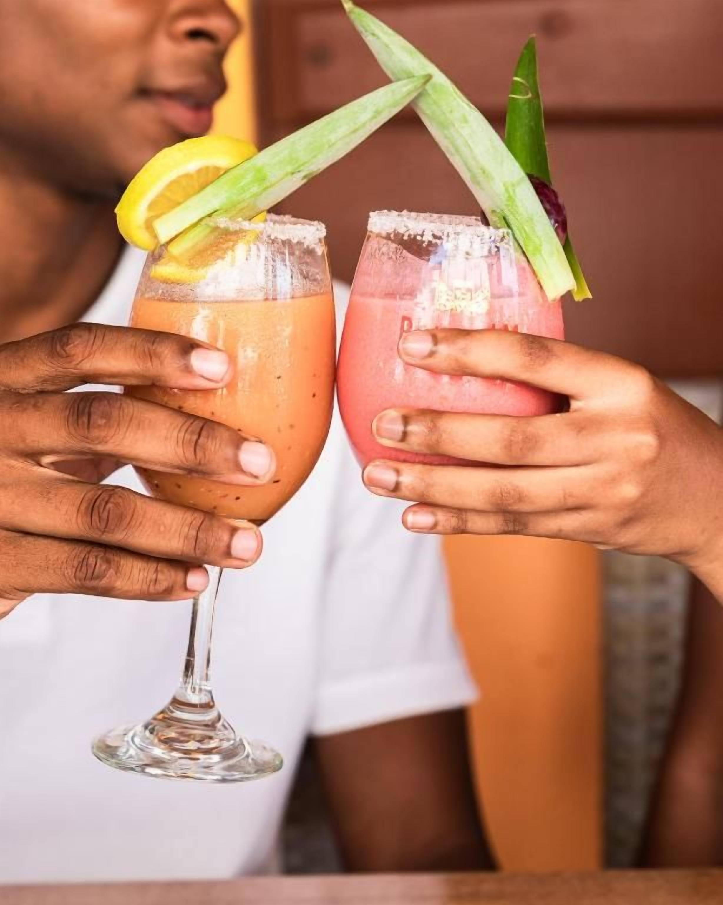 Dos personas sosteniendo vasos de cóctel con adornos.