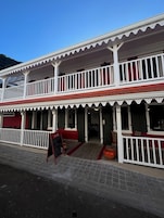 Un edificio de dos pisos con fachada roja y blanca, que cuenta con balcones y una entrada principal.