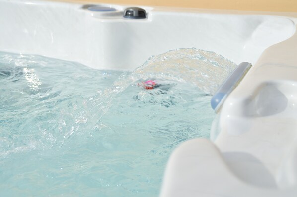 A hot tub with clear water and a visible drain.
