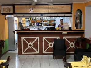 A bar area with a counter, seating, and a reception desk. - Hotel Tante Arlette (Grand Riviere)