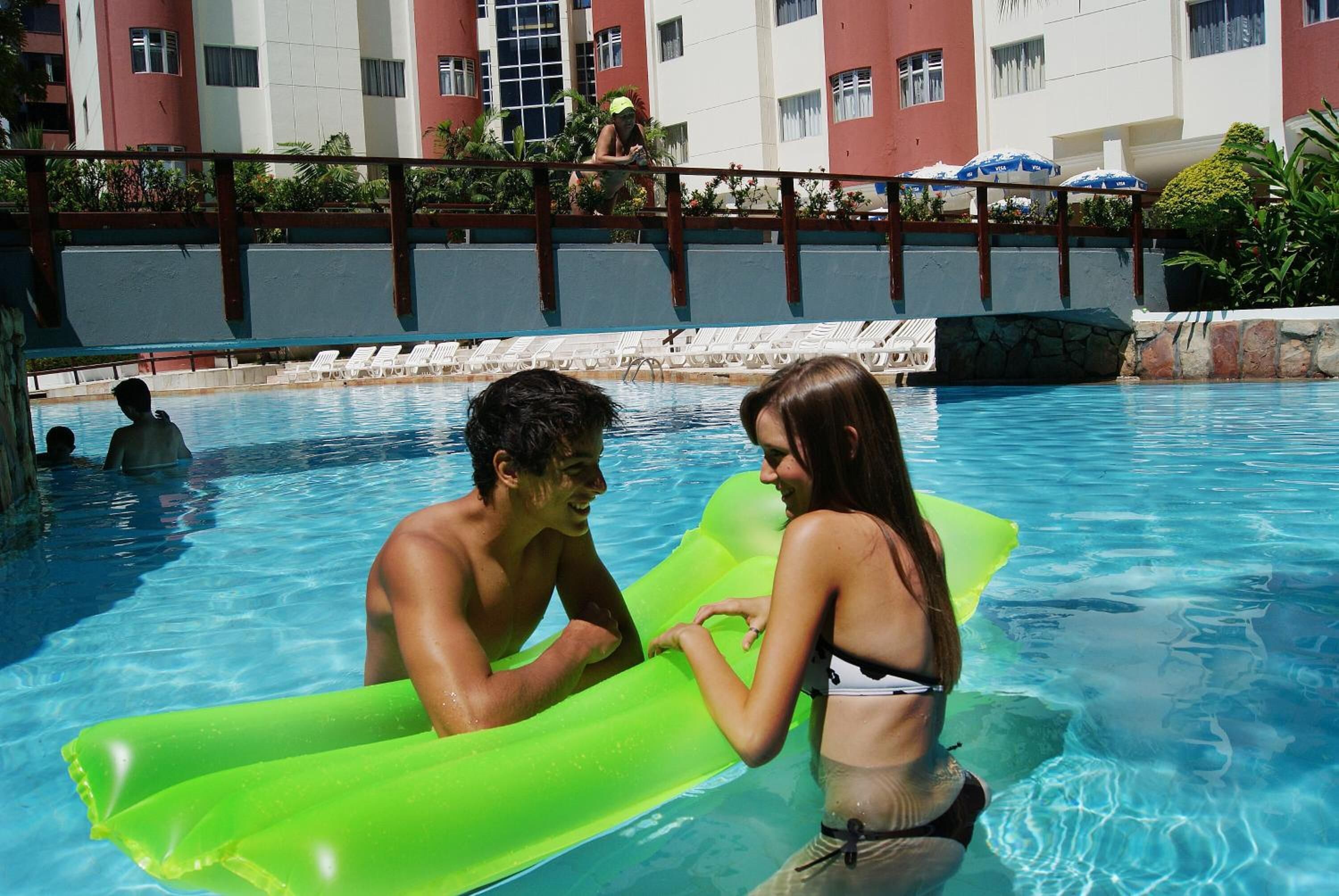 A swimming pool with lounge chairs and a person in the water.