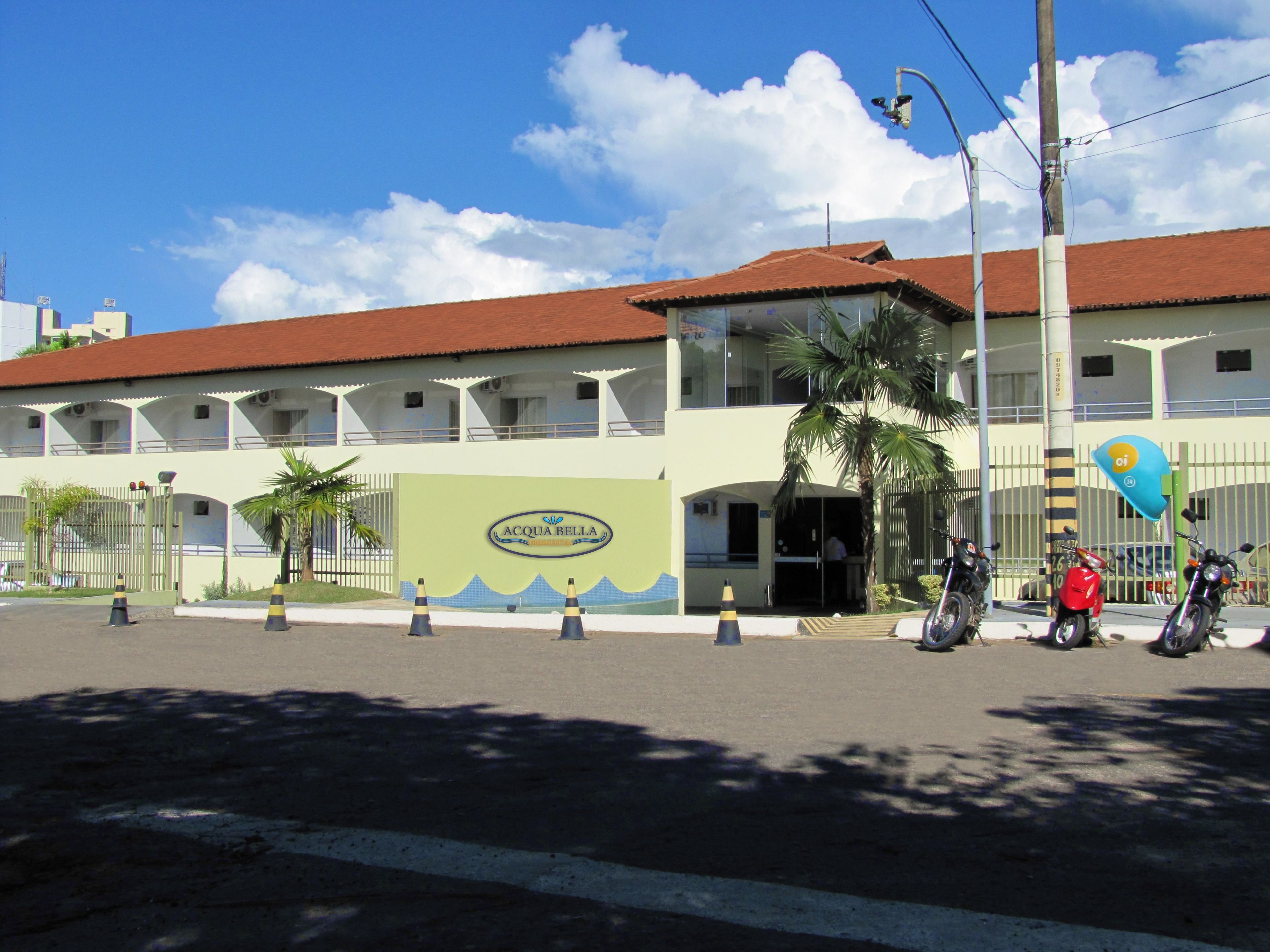 A hotel with a green facade, a red roof, and a sign reading "Acqua Bella."