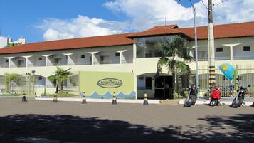 A hotel with a green facade, a red roof, and a sign reading "Acqua Bella."