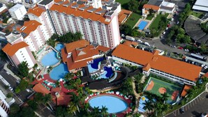 Un hôtel de grande hauteur doté de plusieurs piscines, d’un court de tennis et d’un espace paysager agrémenté de palmiers.