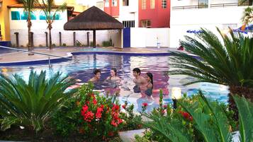 A swimming pool with palm trees and red flowers around it.