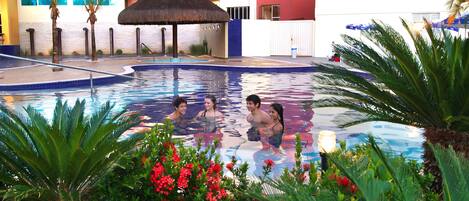 A swimming pool with palm trees and red flowers around it.