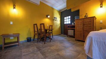 A room with a dining area, a bed, a cabinet, and a window.