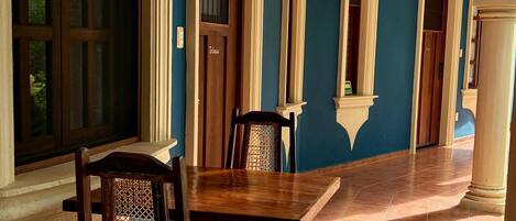 Une pièce avec une table et des chaises en bois, une grande fenêtre et un mur bleu.