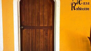 A wooden door with an arch, a tiled entrance, and a wall with a logo and text.