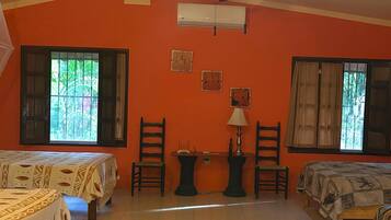 Una habitación con dos camas, ventilador de techo, aire acondicionado y una mesa con sillas.