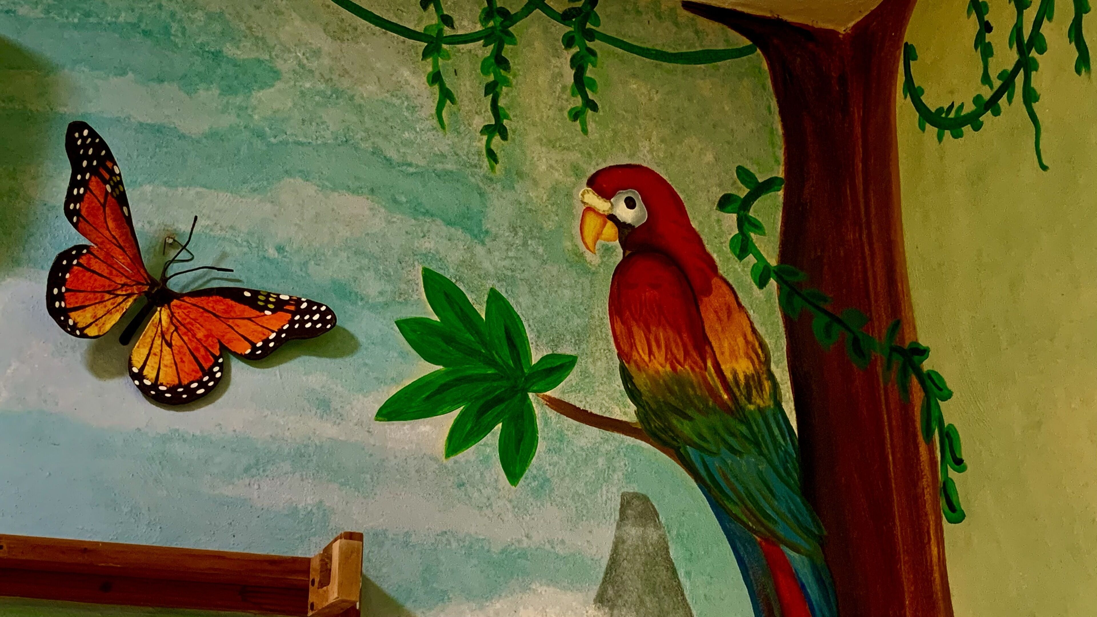 Une fresque représentant un papillon et un perroquet sur un mur.
