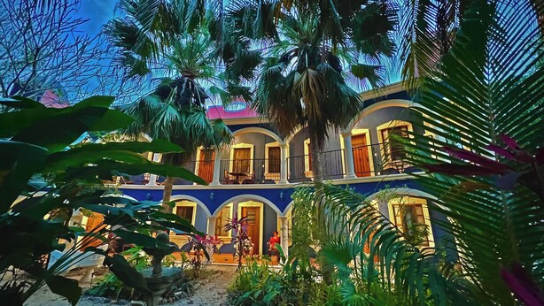 A multi-story building with balconies, surrounded by lush greenery.