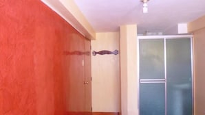 Una habitación con una pared roja, una puerta de madera y una puerta de cristal.