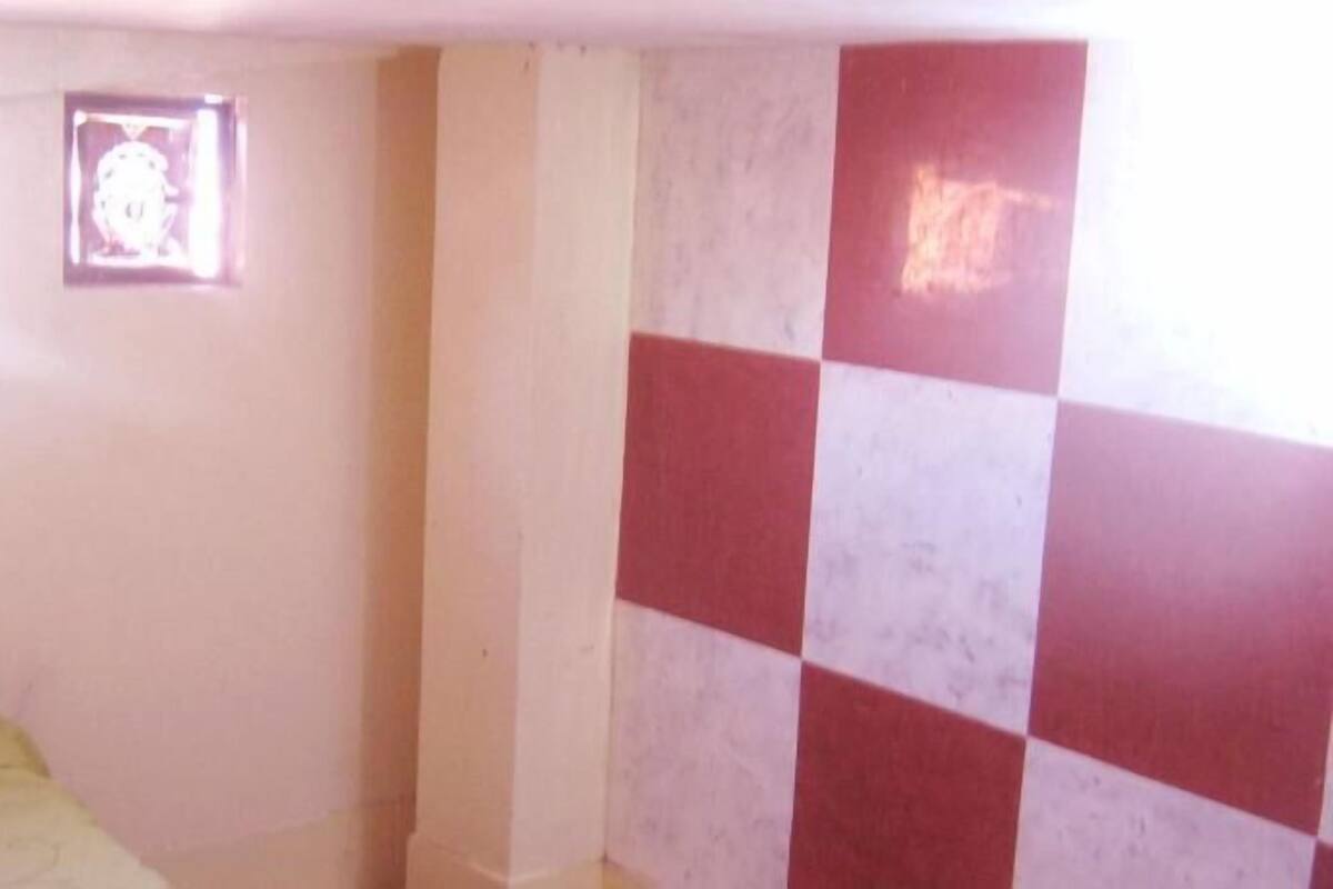 A room with a bed, a wall with a checkered pattern, and a small framed picture on the wall.