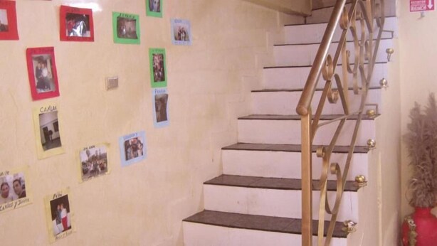 Una escalera con barandilla de latón y una pared decorada con varias fotografías.