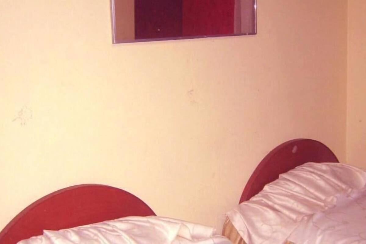 A small room with two single beds, a window, and a chair.