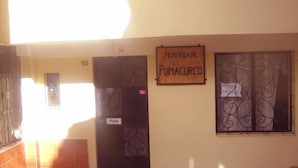 Un pasillo con un cartel que dice "Hospodaje Pumacuro" y un letrero de "EMPUJAR" en una puerta.