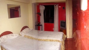 Una habitación con dos camas, televisión y un espejo en la pared.