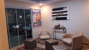 A conference room with glass walls, two beige chairs, a small table, and a poster advertising a 400,000 BRL event. - Pousada DuKalango (Caldas Novas)