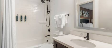 A modern bathroom with a bathtub, toilet, and vanity.