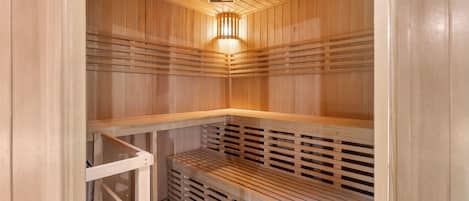 Una sauna de madera con bancos de listones y una lámpara en el centro.