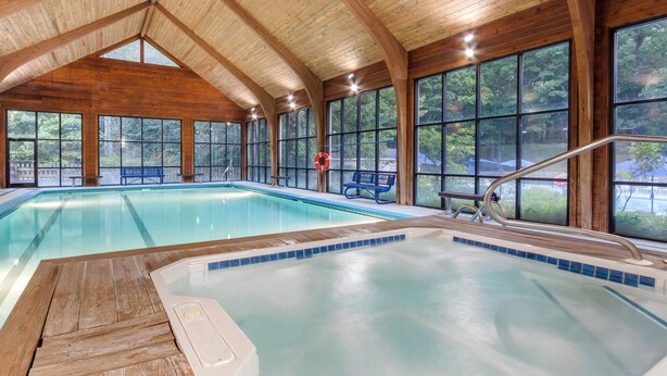 An indoor swimming pool with wooden beams and large windows.