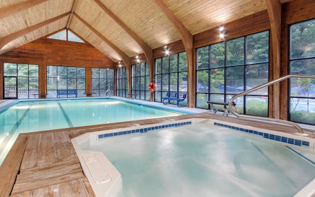 An indoor swimming pool with wooden beams and large windows.