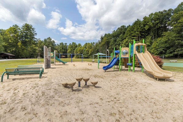 A playground with slides and climbing structures, benches, and a picnic table area.