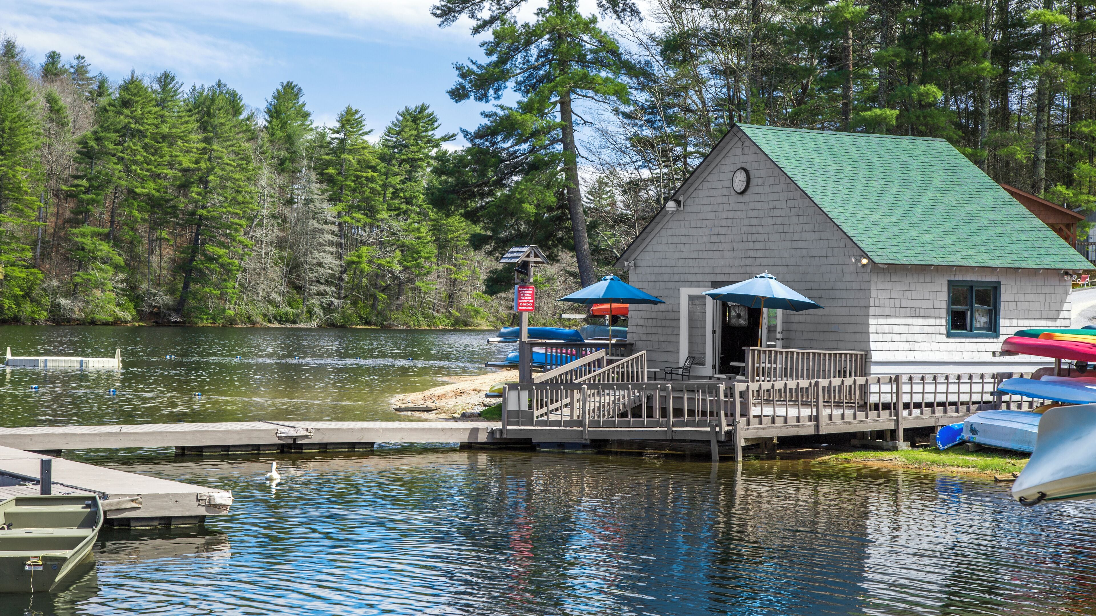 A small cabin with a dock, surrounded by water and trees.