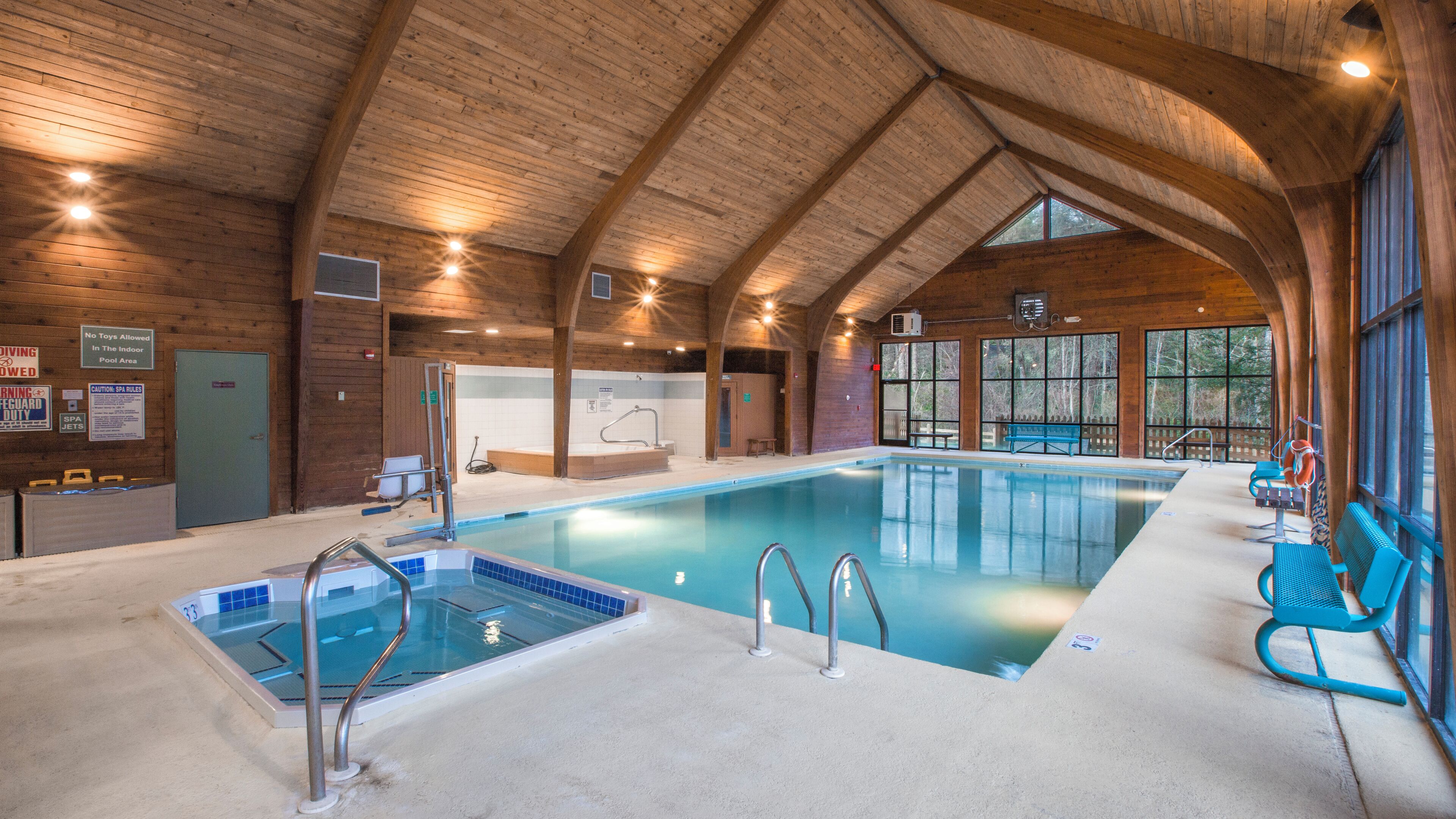 Ein Hallenbad mit Holzboden und großen Fenstern.