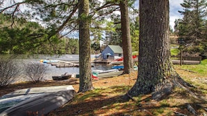A lakeside cabin with docked boats, surrounded by trees.
