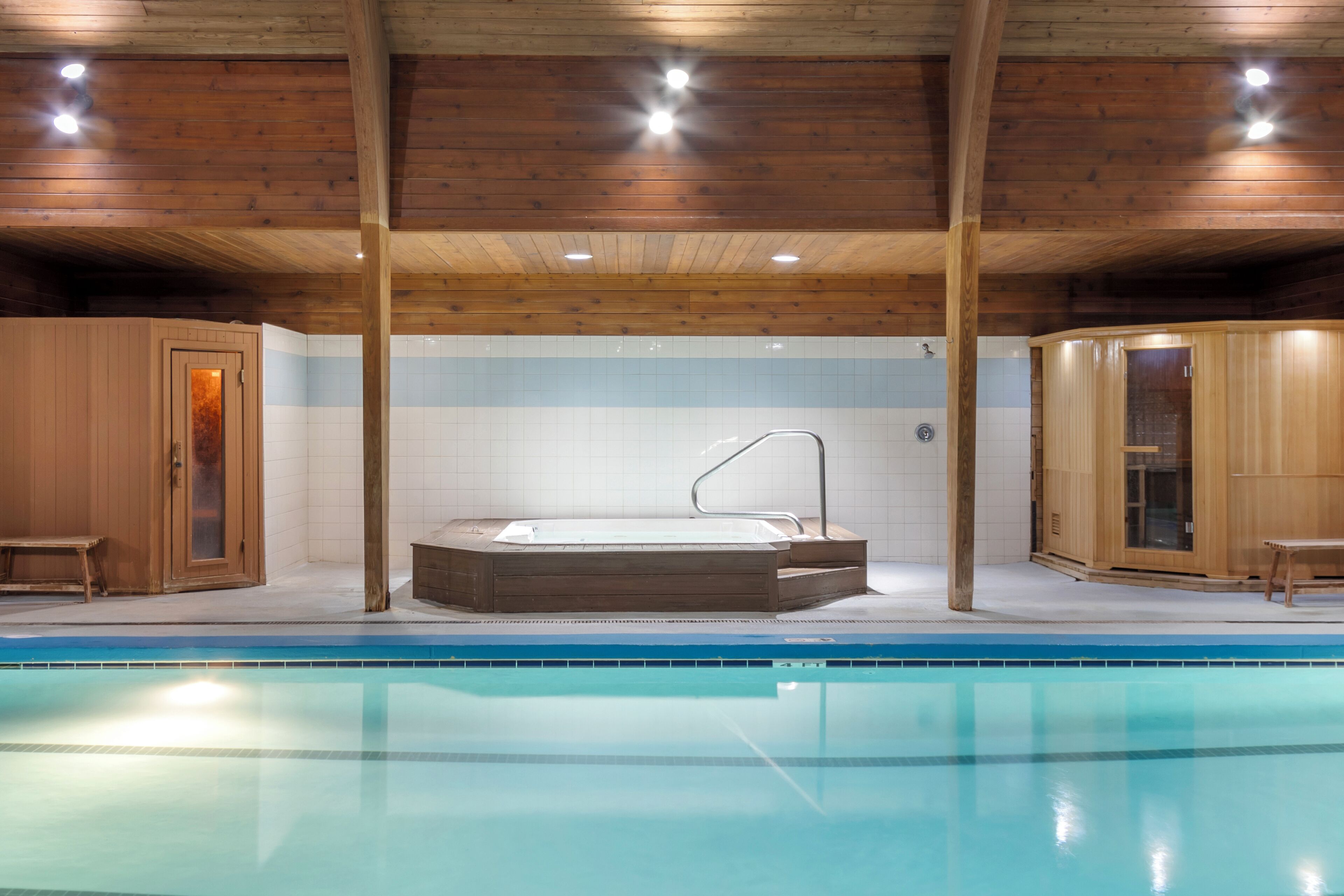 Ein Schwimmbad mit Holzhütten und einem Whirlpool.