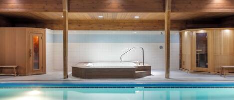 Ein Schwimmbad mit Holzhütten und einem Whirlpool.
