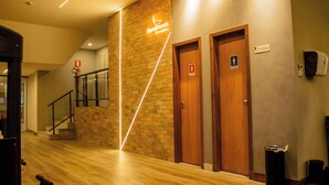 A hallway with wooden doors, a staircase, and a neon sign for "PenaBranca Academia". - Pena Branca Hotel e Eventos (Santo Antonio de Jesus)